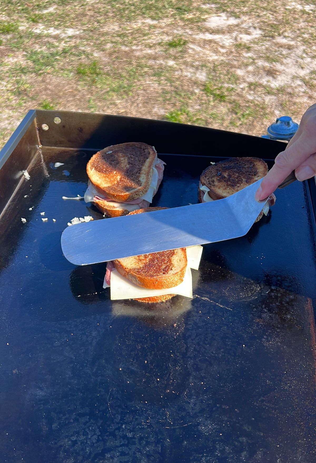 spatula pressing on corned beef sandwich.