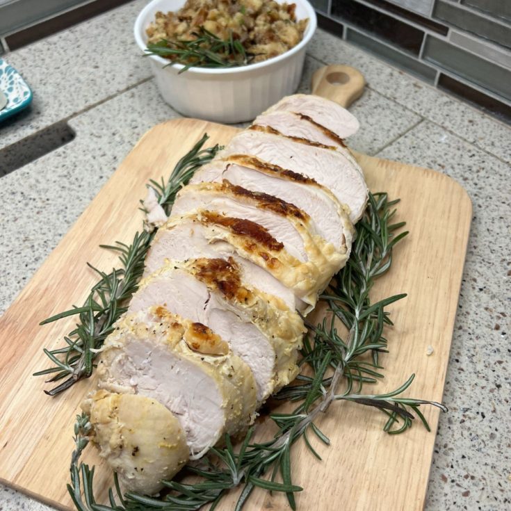 A roasted turkey with rosemary on a cutting board.