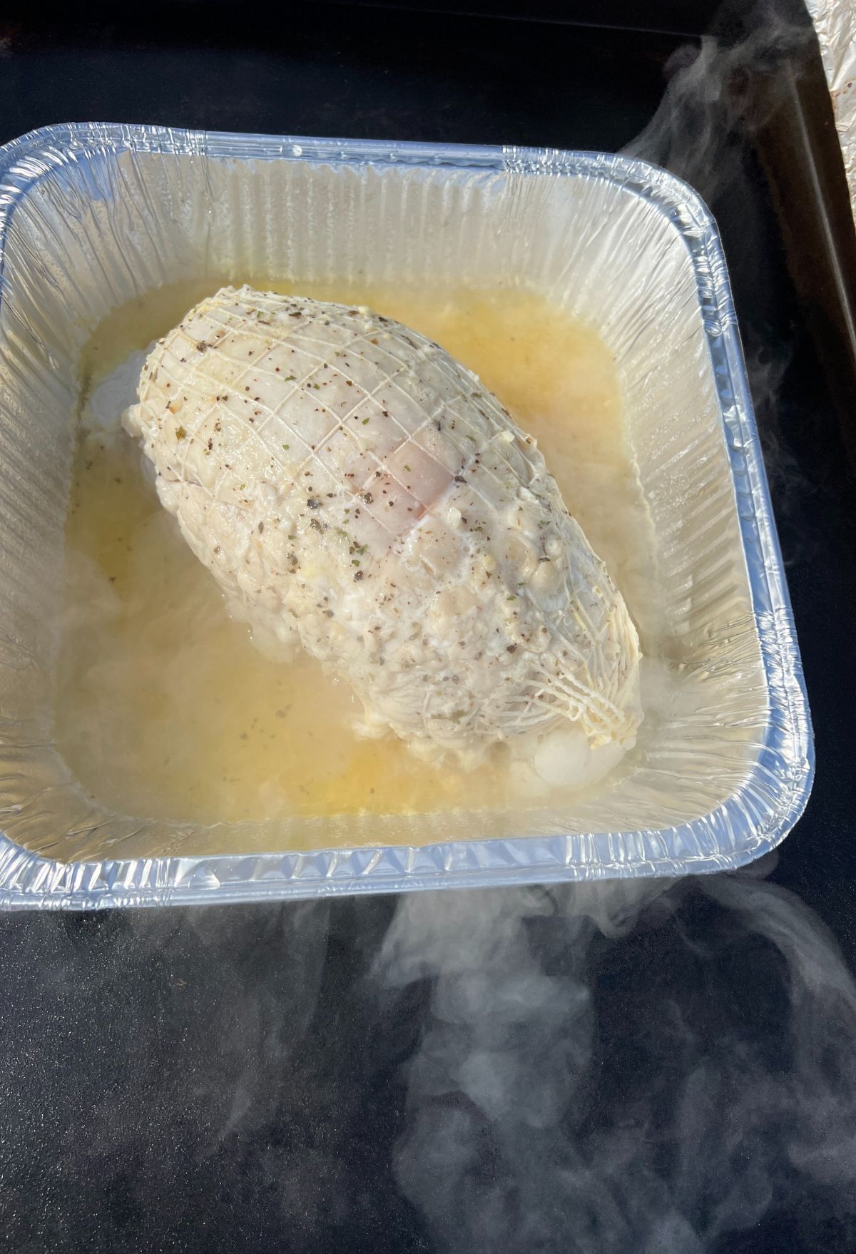 A chicken in a plastic container with steam coming out of it.