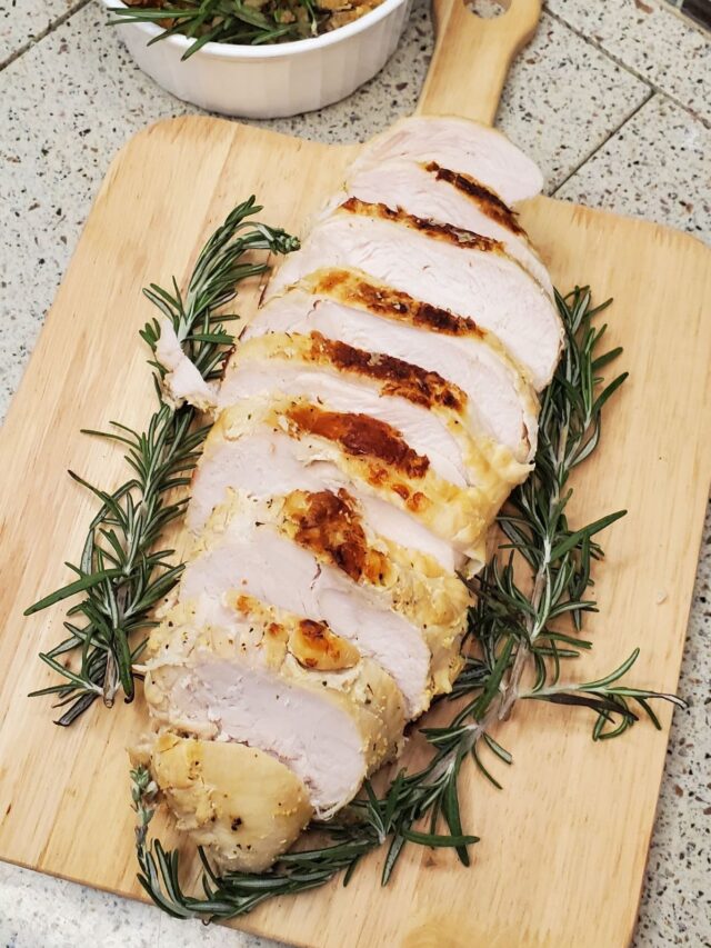 Grilled turkey with rosemary on a cutting board.