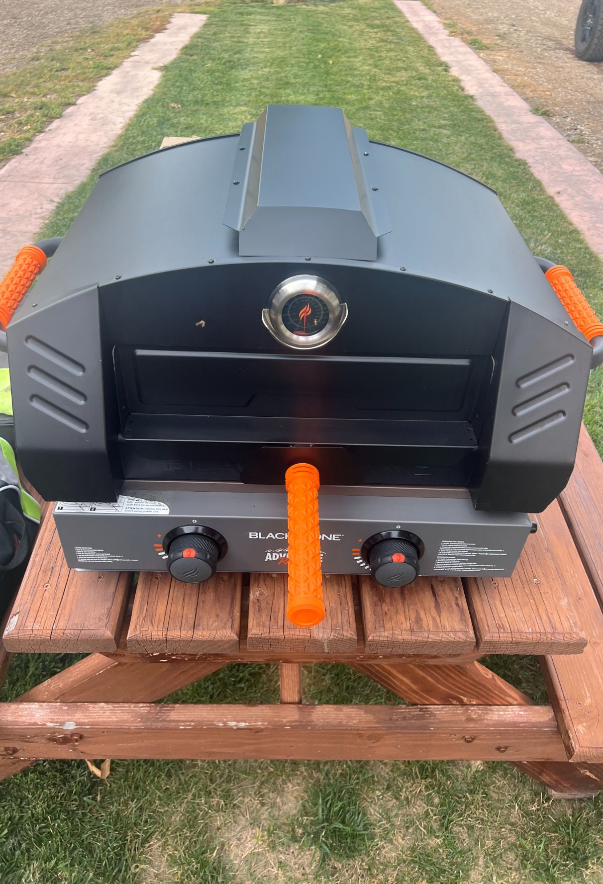 A gas grill sitting on top of a picnic table.
