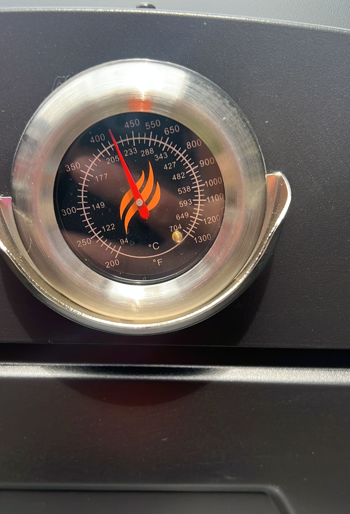 A stainless steel thermometer with a flame on it.