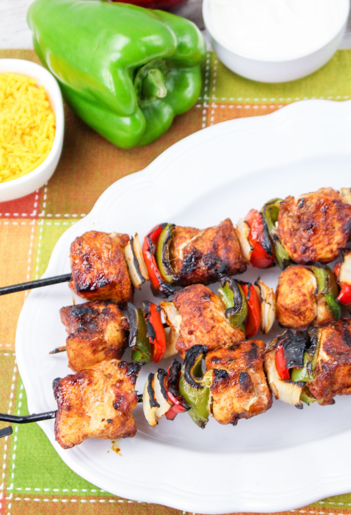 Chicken skewers on a plate with peppers and onions.