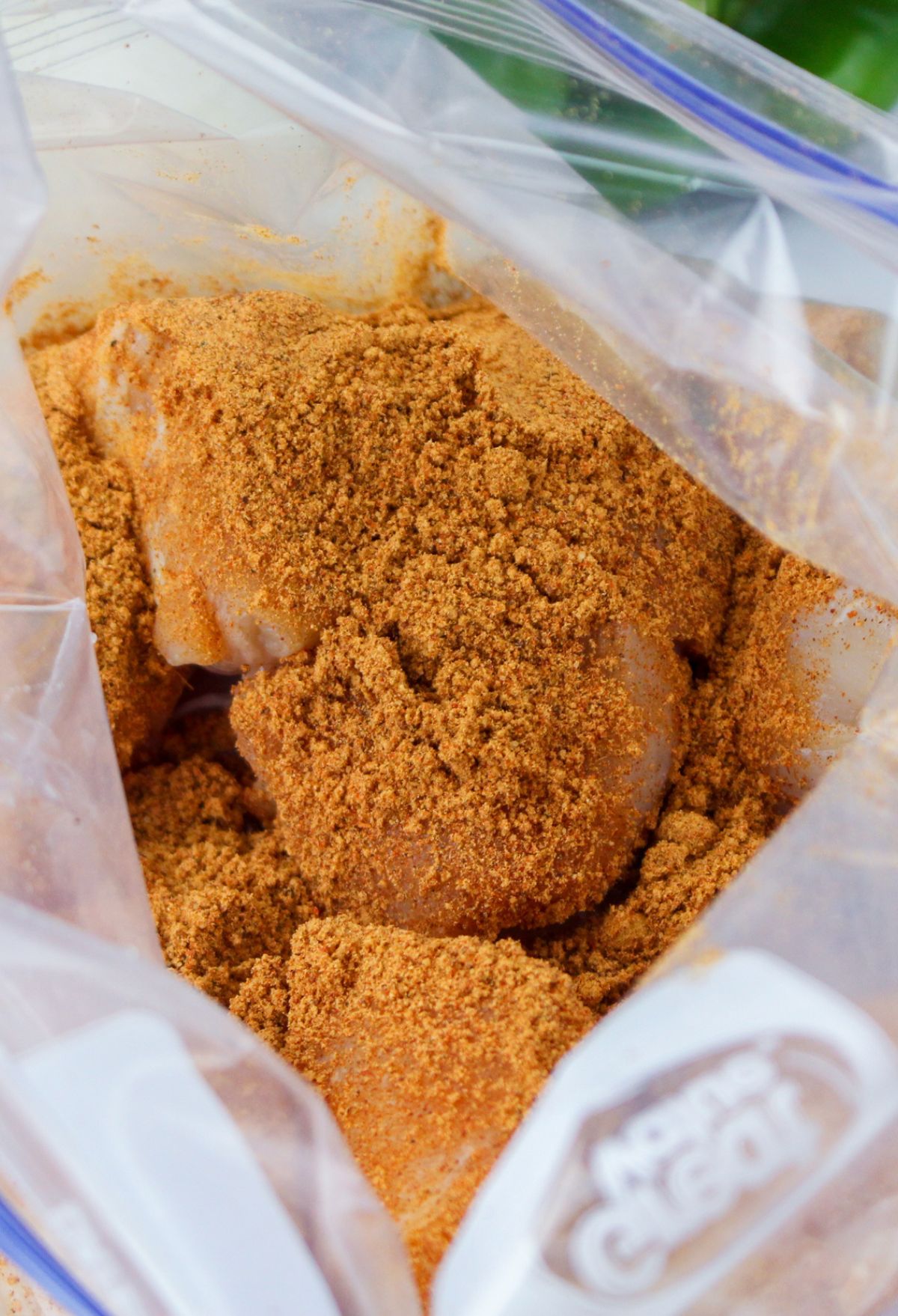 A bag filled with seasoned chicken in a plastic bag.
