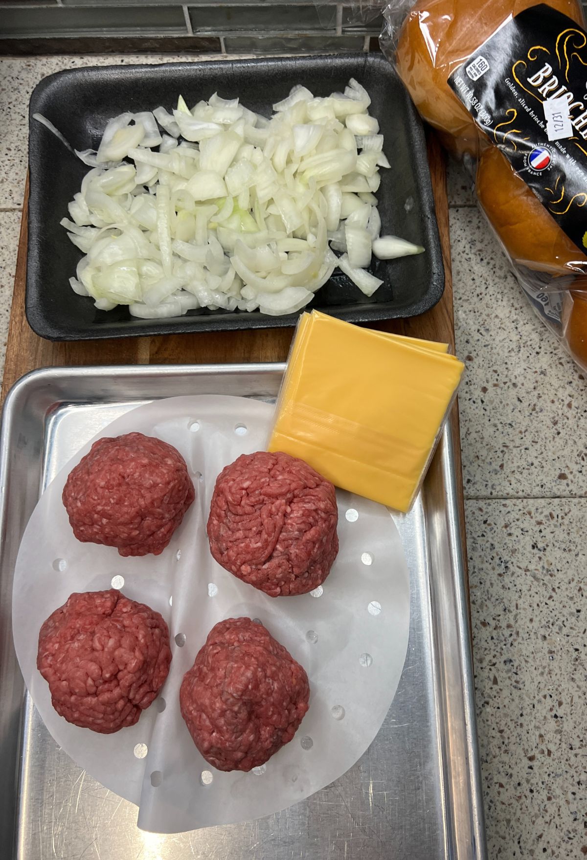 Meatballs with onions and cheese on a baking sheet.