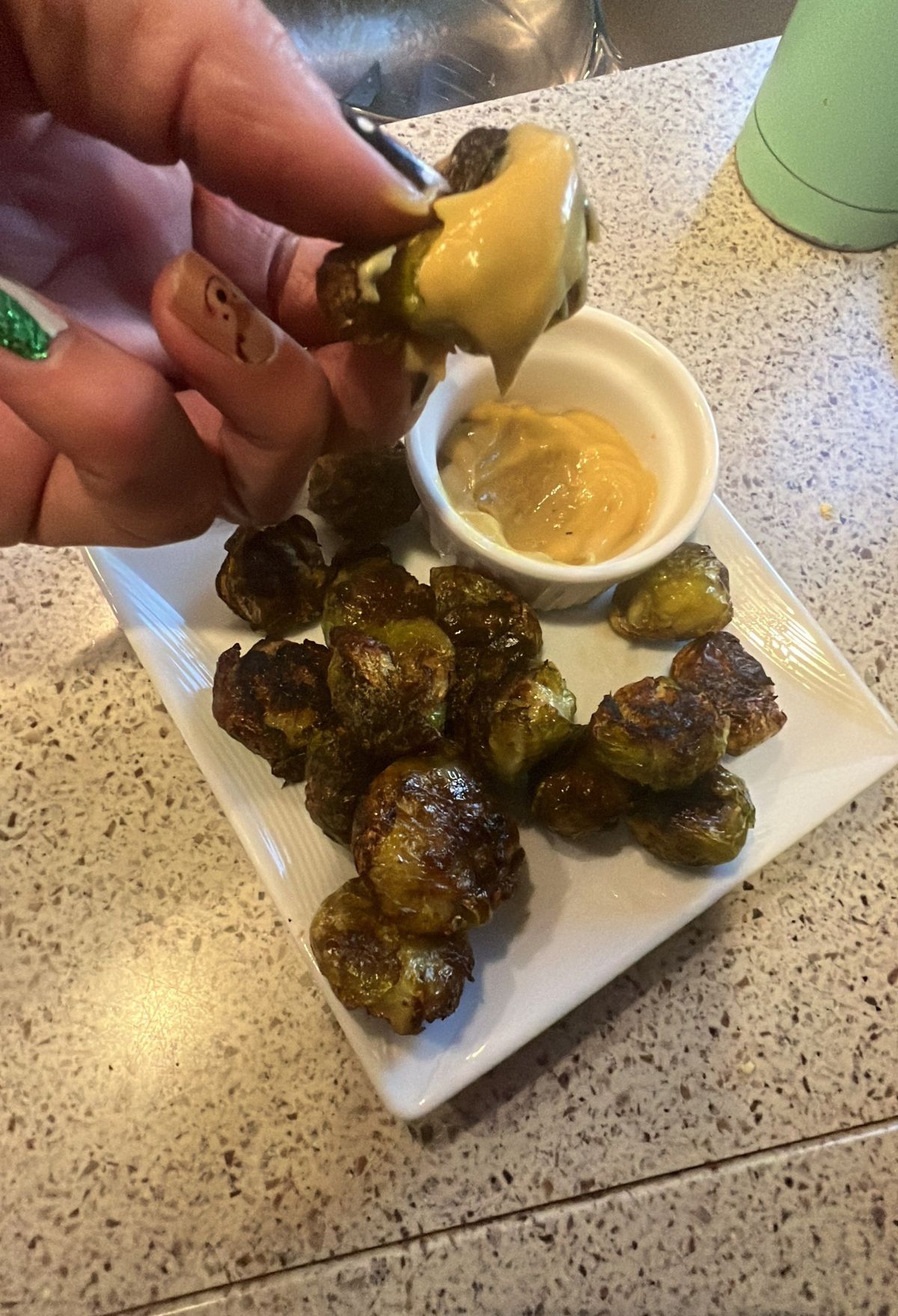 A person is dipping brussels sprouts into a sauce.
