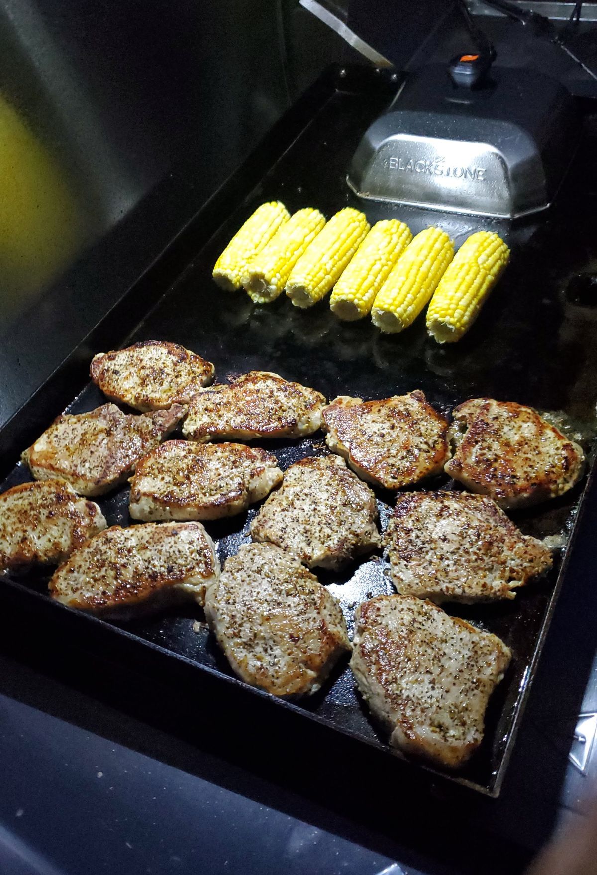 A tray of grilled meat and corn on the grill.