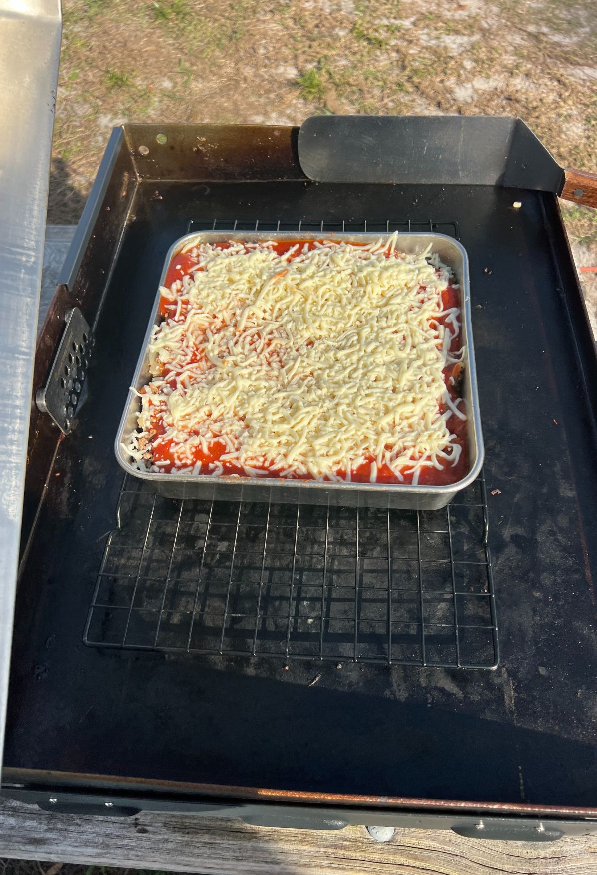 A pizza is being cooked on a grill.
