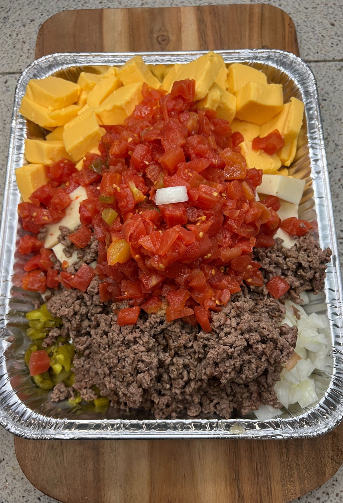 A tray with meat, cheese, tomatoes and onions.