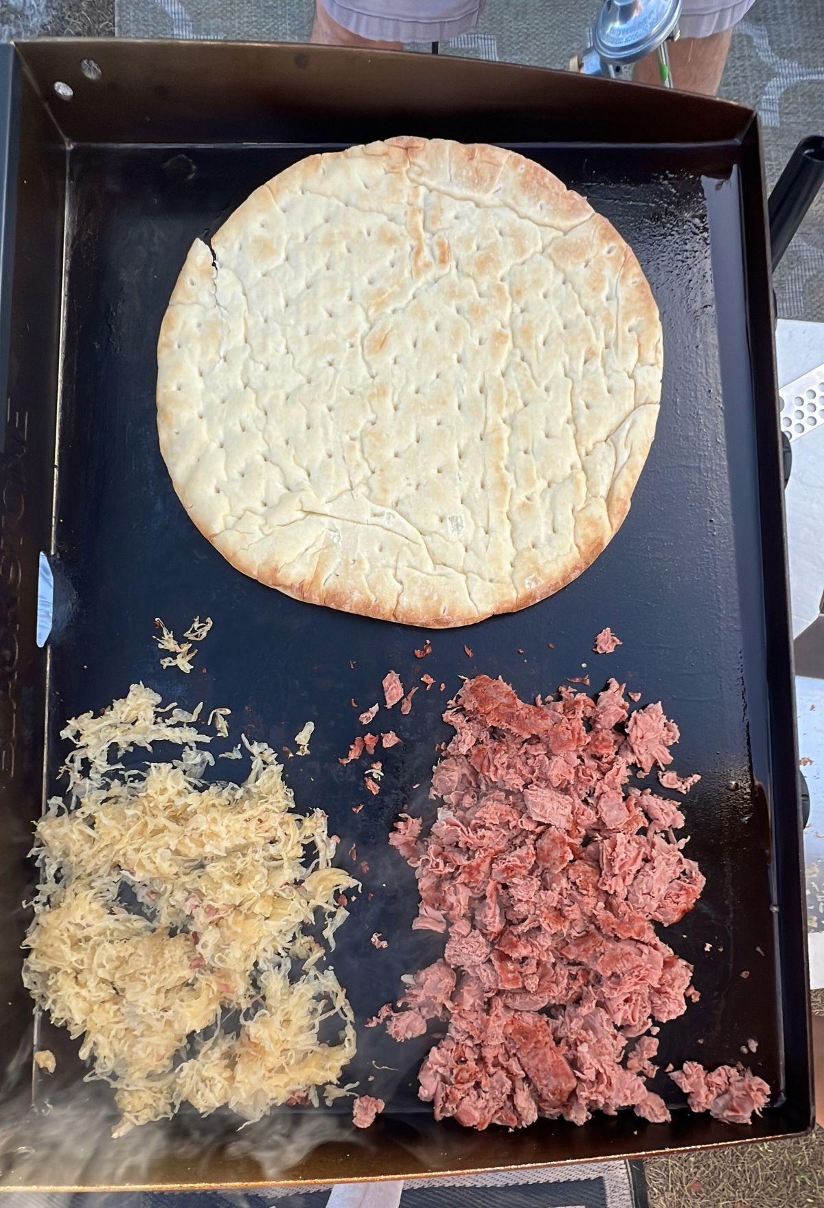 A pizza with meat and cheese on a baking sheet.