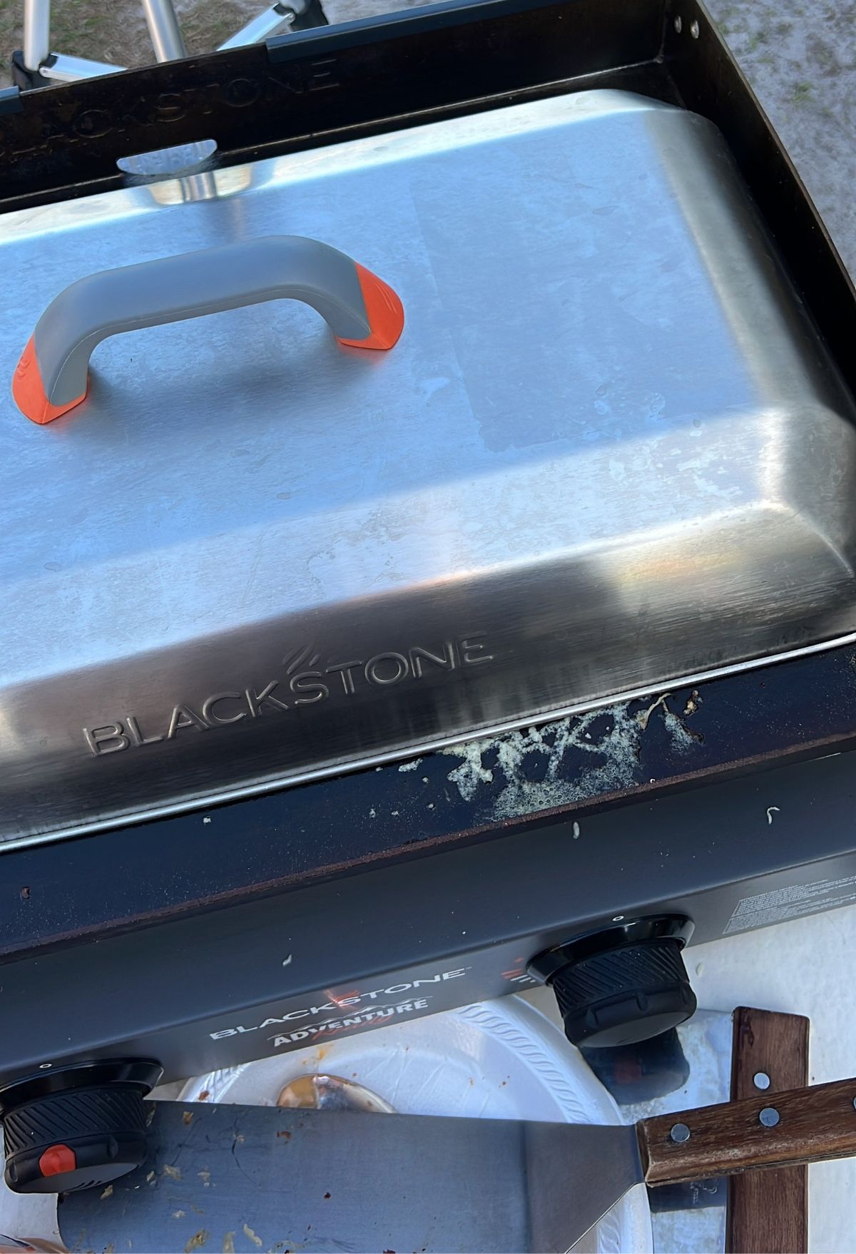 A blackstone grill with a knife on top of it.