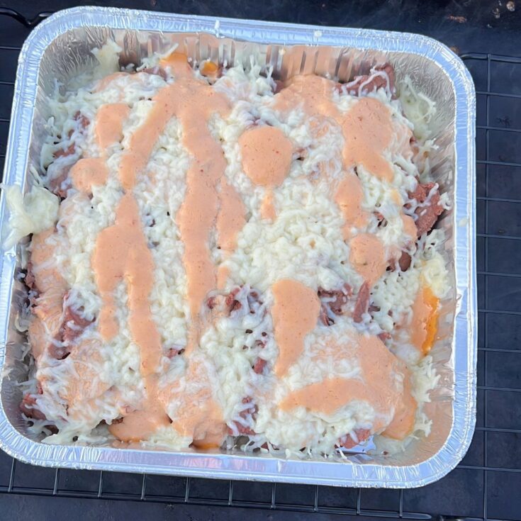 A casserole dish with cheese and sauce sitting on top of a grill.