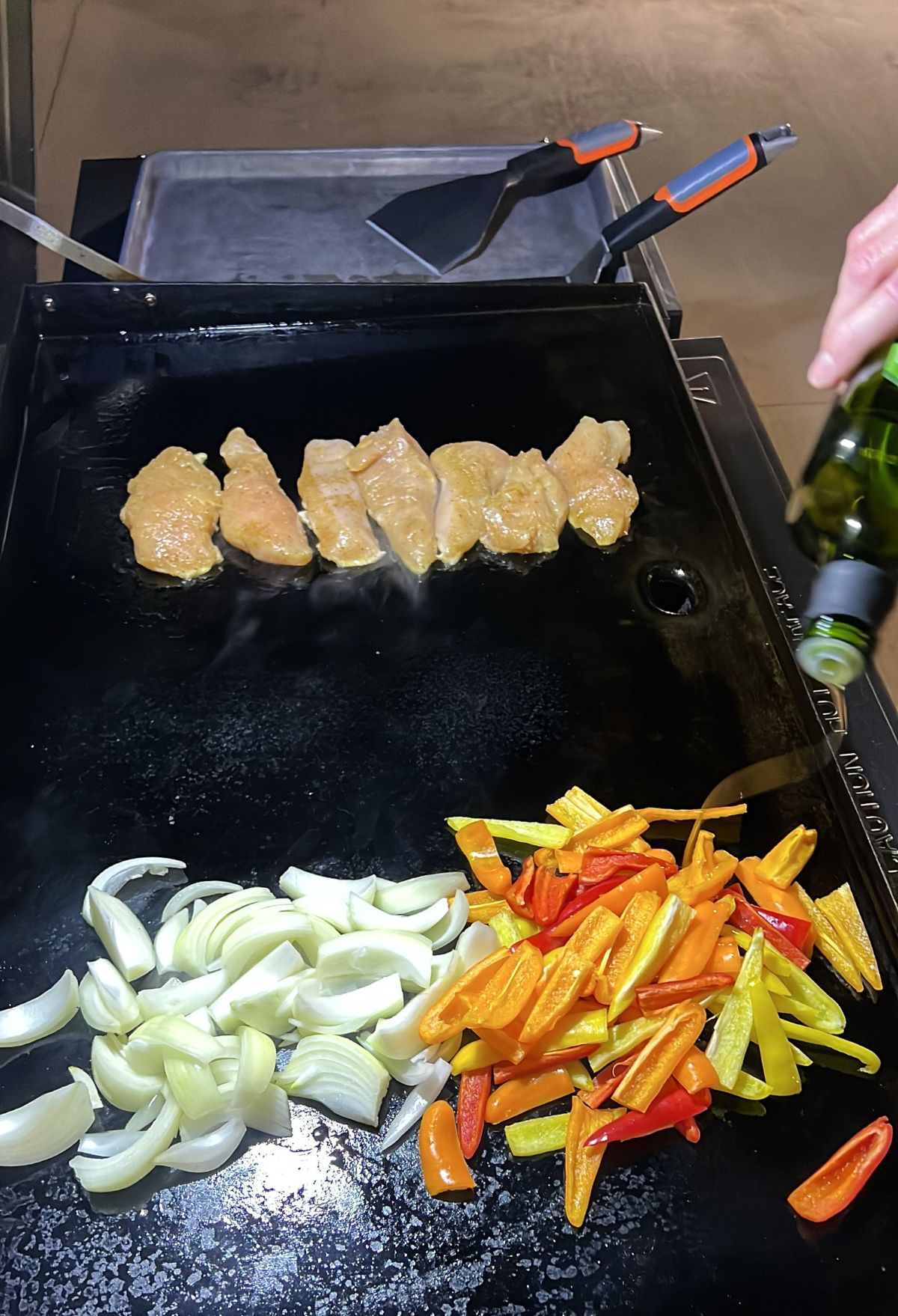 Cooking chicken and vegetables on a stovetop griddle.