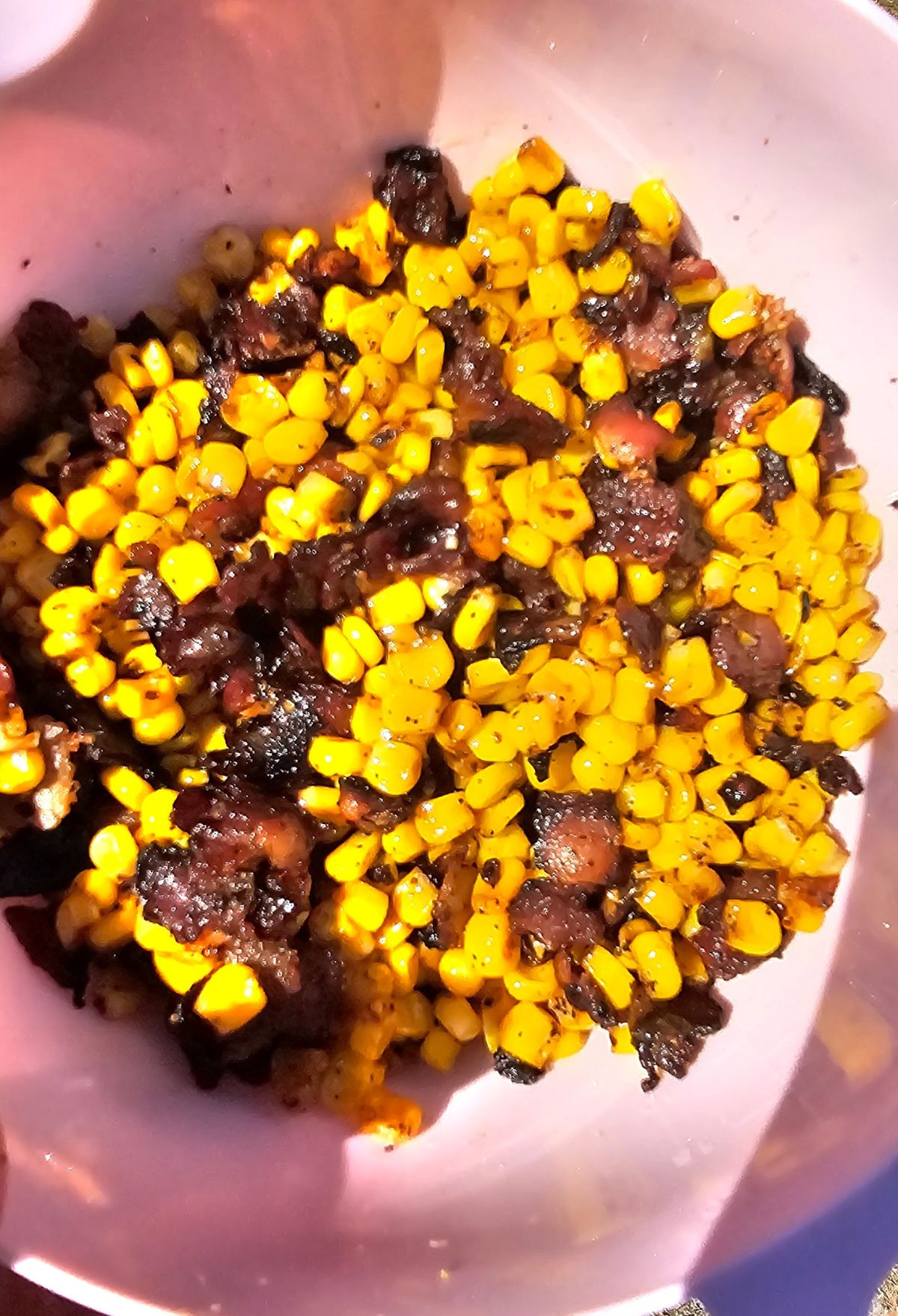 A bowl containing a mixture of corn and charred pieces of food.