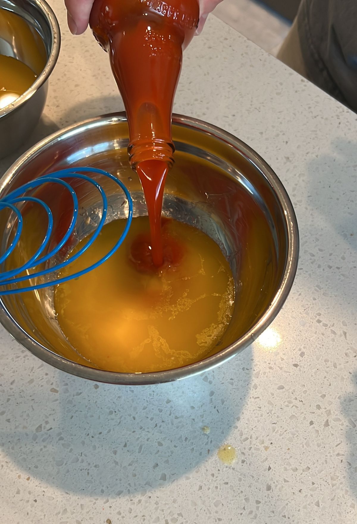 A person pouring sauce into a bowl.