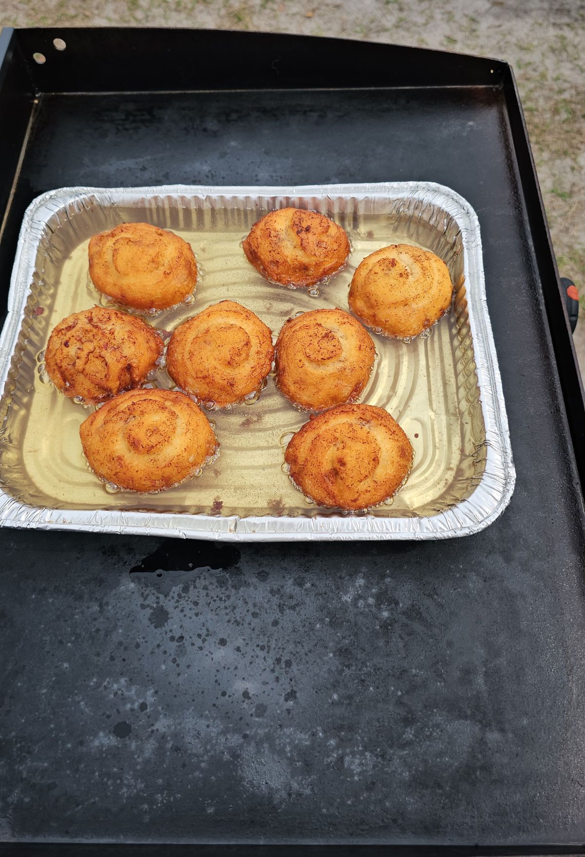 Grilled cheese rounds on a disposable aluminum tray.
