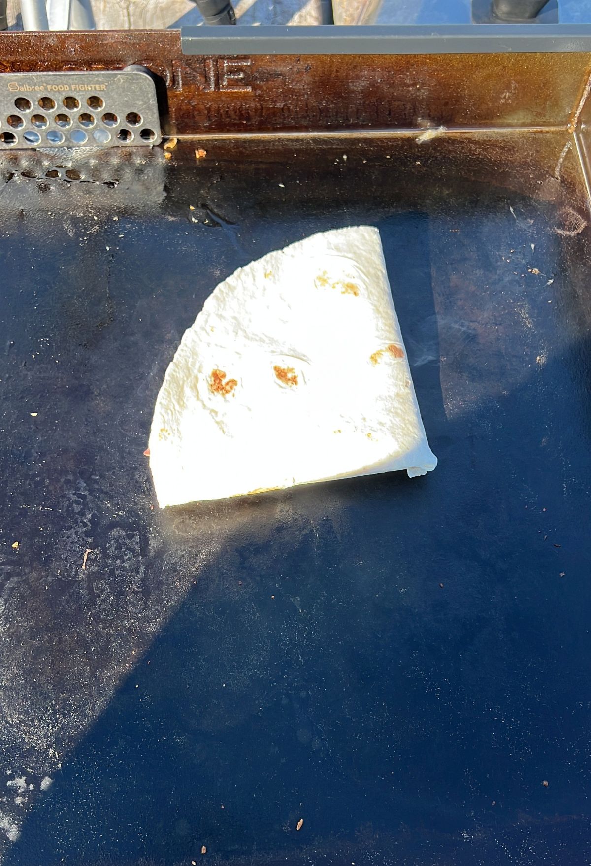 A half quesadilla on a griddle.